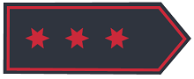 Schulterklappe in dunkelblauer Grundfarbe mit drei sechszackigen Sternen in Rot, mittig in Reihe, Abzeichenumrandung in Rot